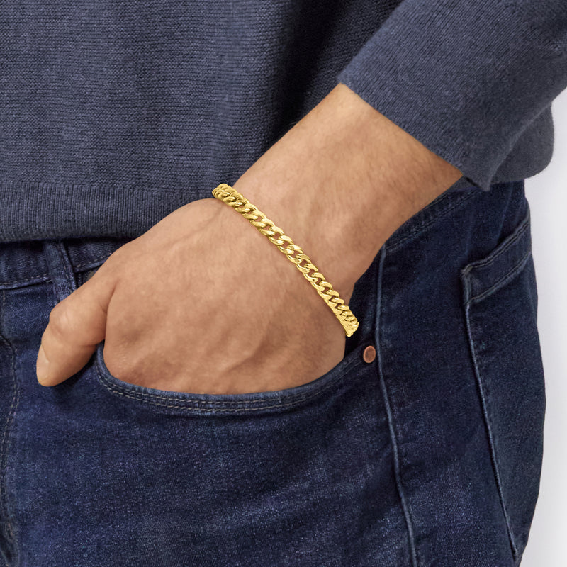 Yellow gold Cuban-link bracelet worn on wrist, chain link design
