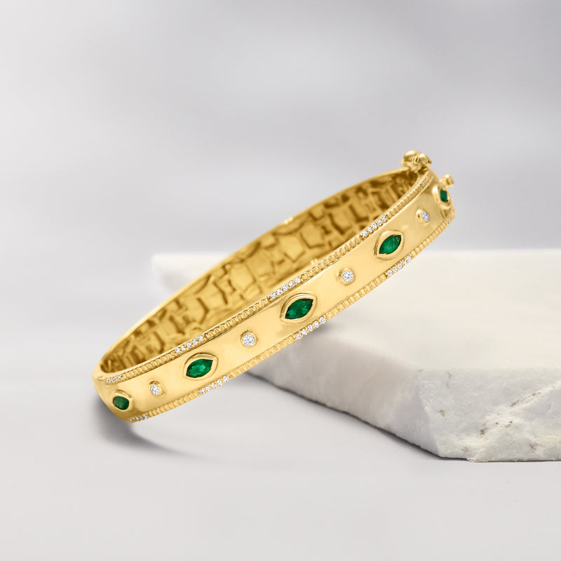 Gold bangle bracelet with green oval accents and small round diamond settings