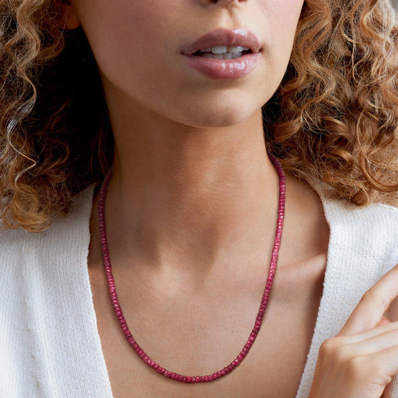 Ruby bead necklace on model, close-up of red round bead collar