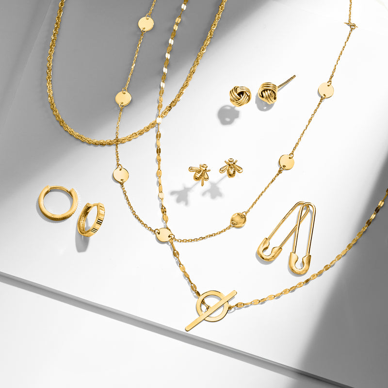 Gold disc station necklace with small round discs, laid on jewelry display