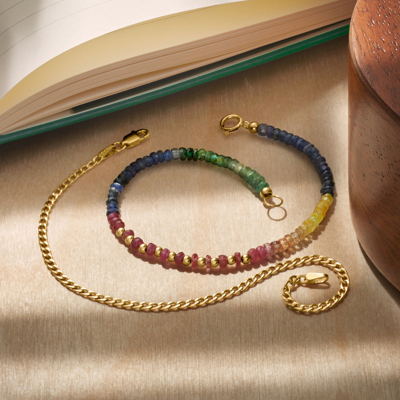 Yellow gold curb-link chain bracelet with lobster clasp, laid on tabletop