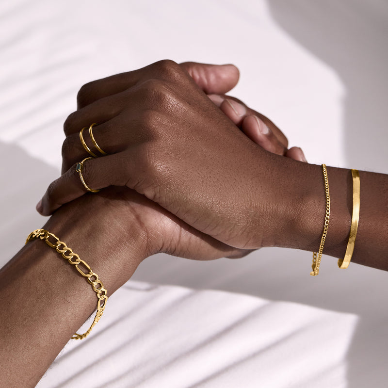 Yellow gold curb-link bracelet worn on wrist; oval chain links with clasp