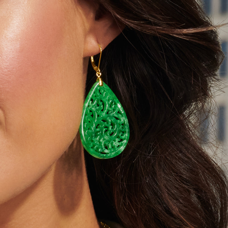 Carved green jade teardrop earrings with gold leverback, close-up on ear