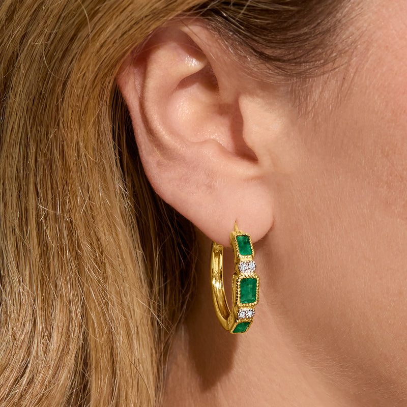 Gold hoop earrings worn on ear, featuring emerald-green rectangles with diamond rows