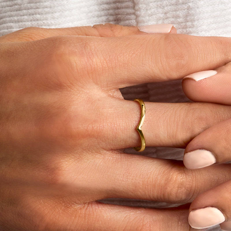 Chevron-style yellow gold ring on finger with smooth raised V shape