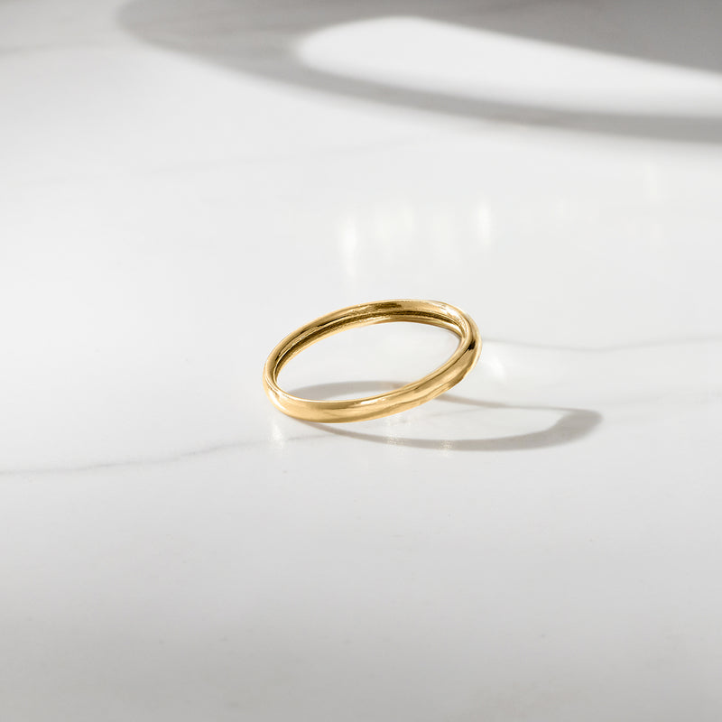 Polished yellow gold band ring lying flat, bright reflective finish