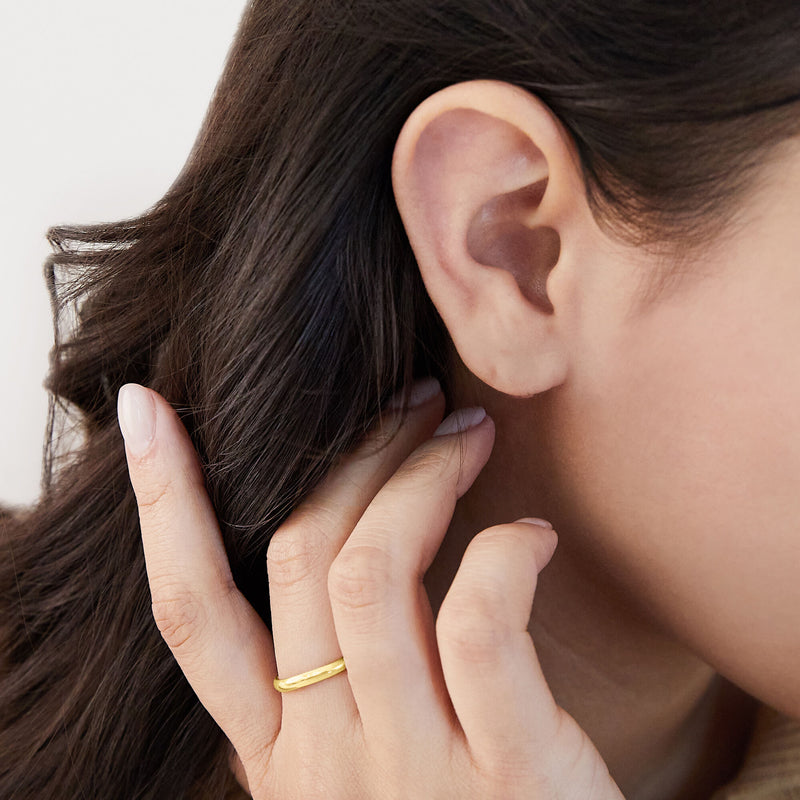 Yellow gold polished band ring worn on finger, smooth slim profile