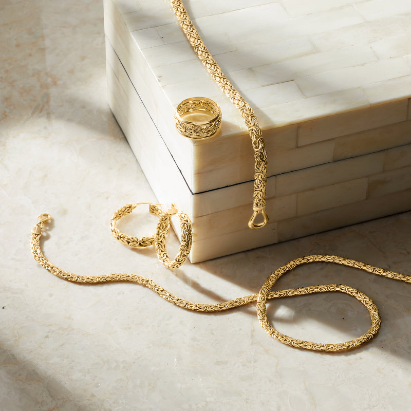 10kt yellow gold Byzantine bordered ring with woven design, resting on jewelry box