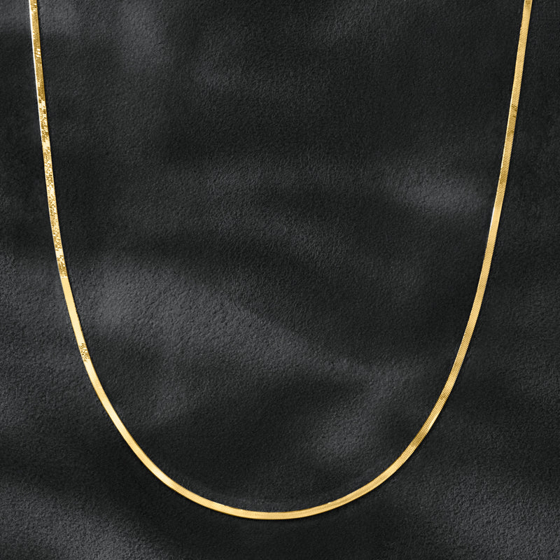 Gold herringbone necklace chain close-up, smooth rounded links arc