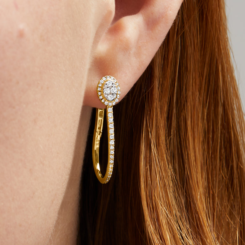 Close-up of elongated gold hoop with circular diamond cluster and dangling row stones