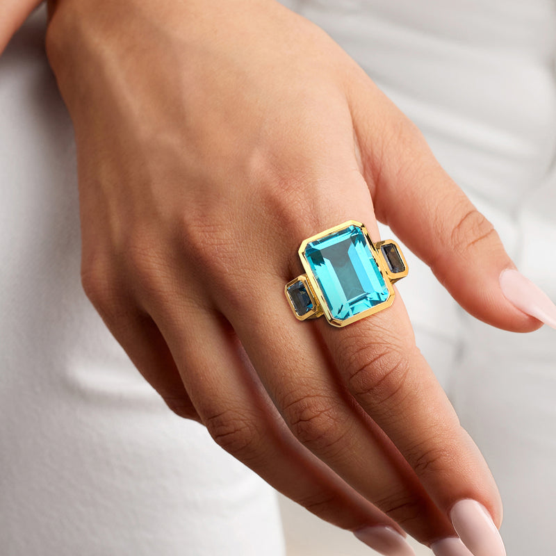 18kt gold over sterling three-stone ring with blue square-cut center quartz and topaz stones on finger