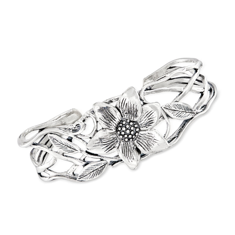 Silver cuff bracelet with textured floral centerpiece and polished ribbon-like links