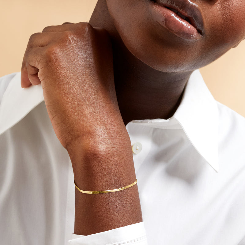 Yellow gold herringbone bracelet on wrist, slim chain with clasp