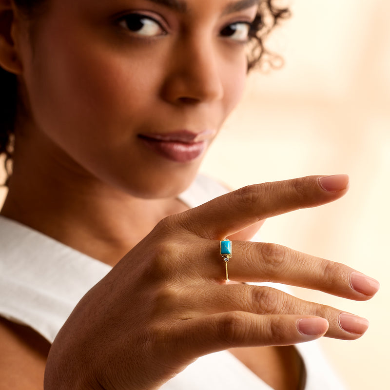Turquoise square gemstone ring on hand in 14kt yellow gold with diamond accents