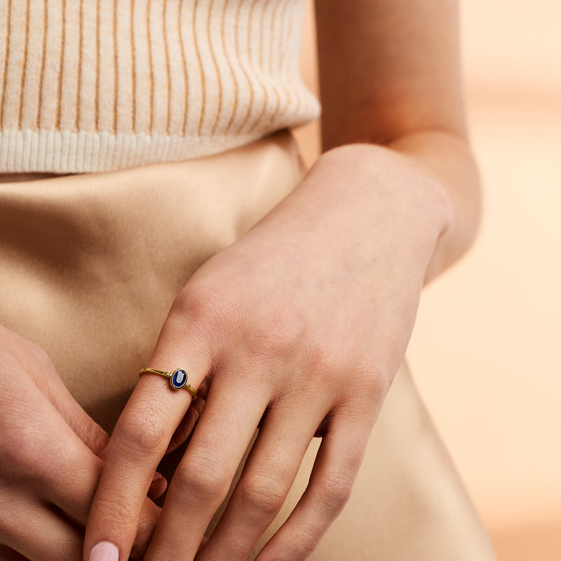14kt yellow gold ring with oval blue sapphire on finger, diamond side accents
