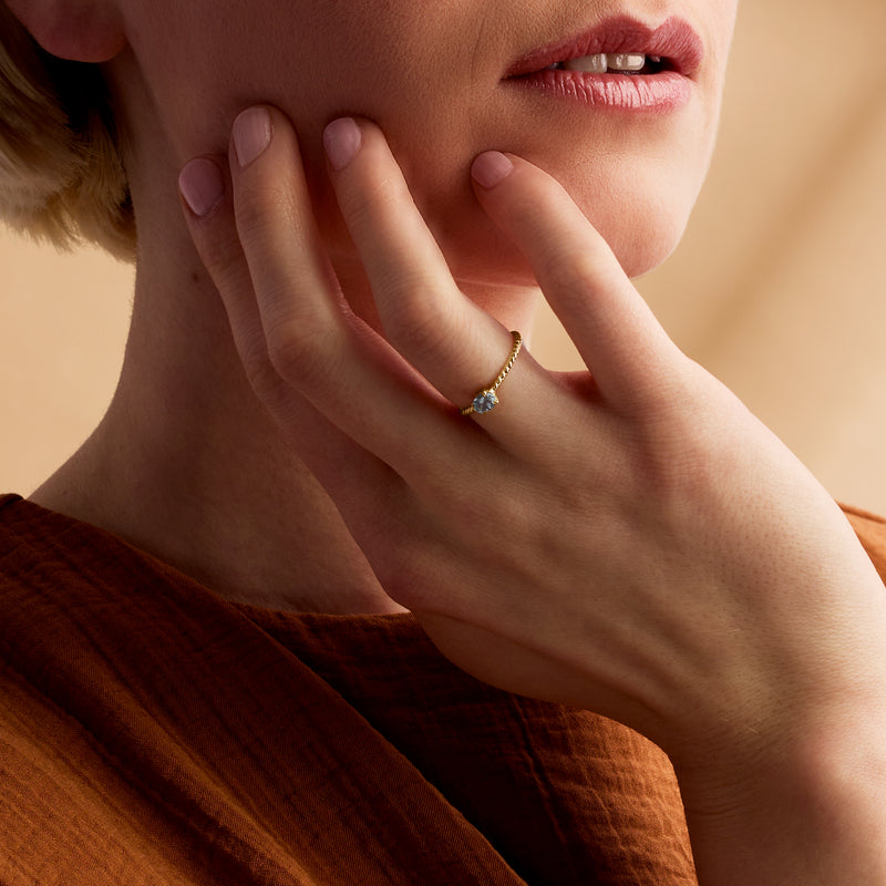 Aquamarine solitaire ring on hand with roped yellow-gold band