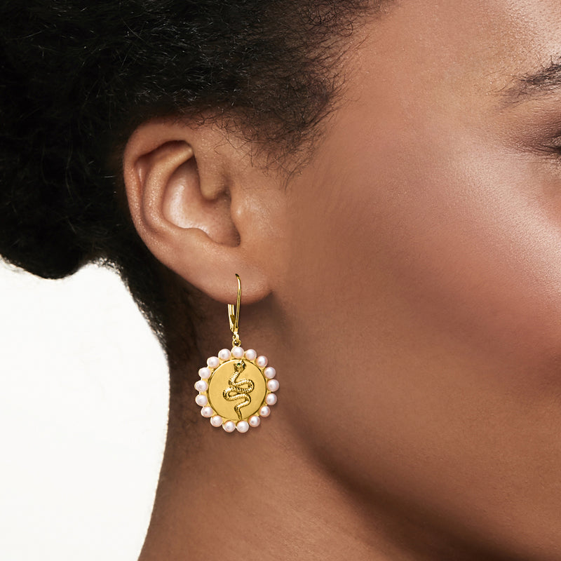 Gold drop leverback earrings on ear, round pearls with green snake emblem