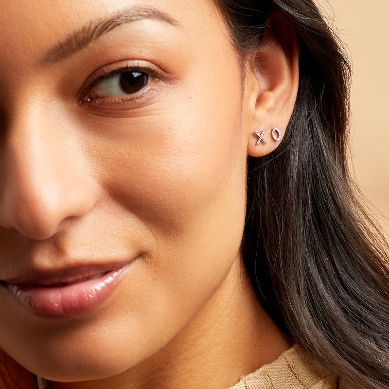 Sterling silver XO diamond stud earrings on ear, X and O mismatched studs