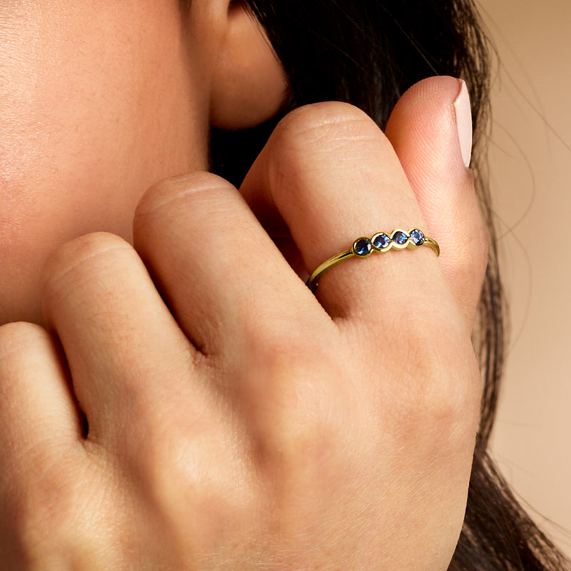 Yellow gold sapphire ring with small round blue stones, worn on finger