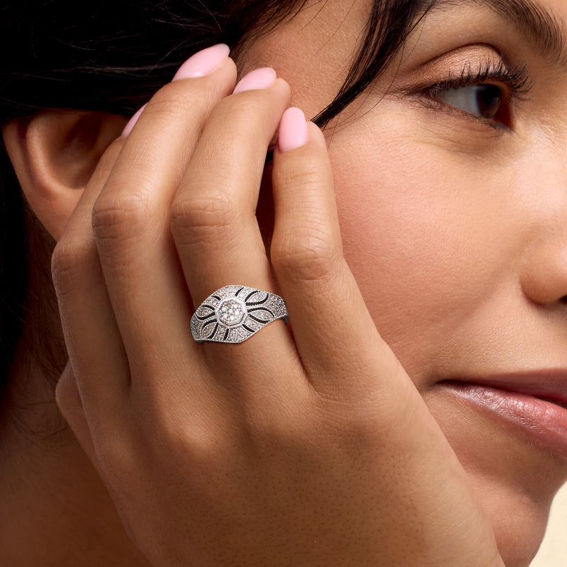 Woman’s hand wearing a sterling silver vintage diamond milgrain ring with a round center stone