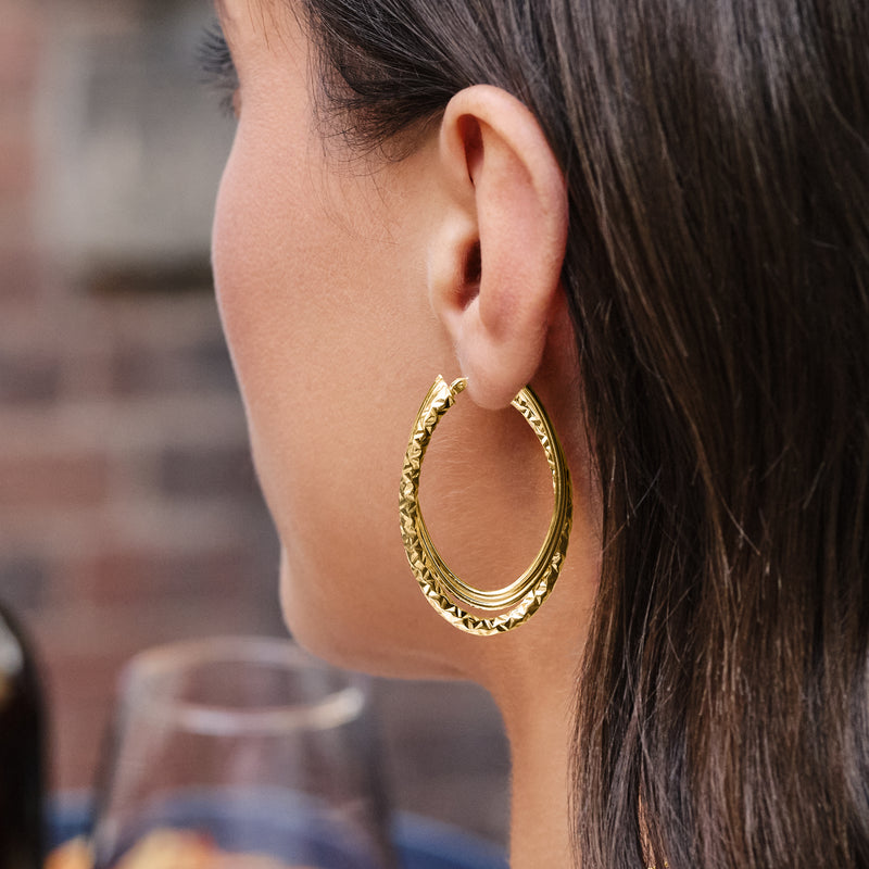 Yellow gold multi-oval hoop earrings with layered oval rings, worn on ear