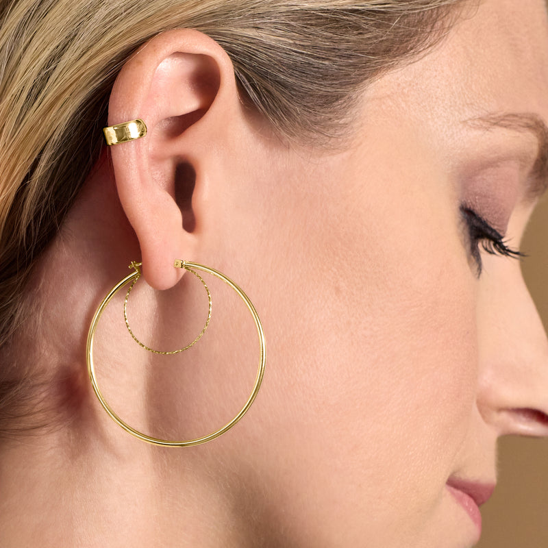 Yellow gold double-hoop earrings on ear, one large hoop with inner hoop