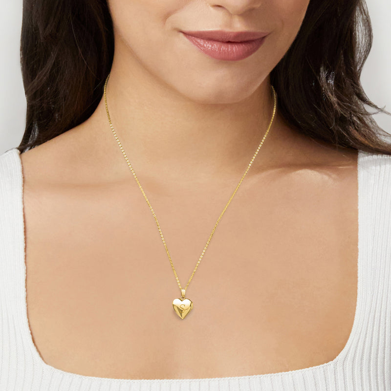 Gold heart locket necklace worn at the neckline, small heart pendant on chain