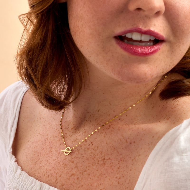 14kt yellow gold toggle necklace with small ring-and-bar charm near collar