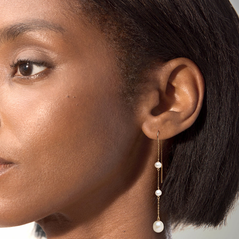 Cultured pearl threader earrings on model ear, three pearl drops in 14kt yellow gold