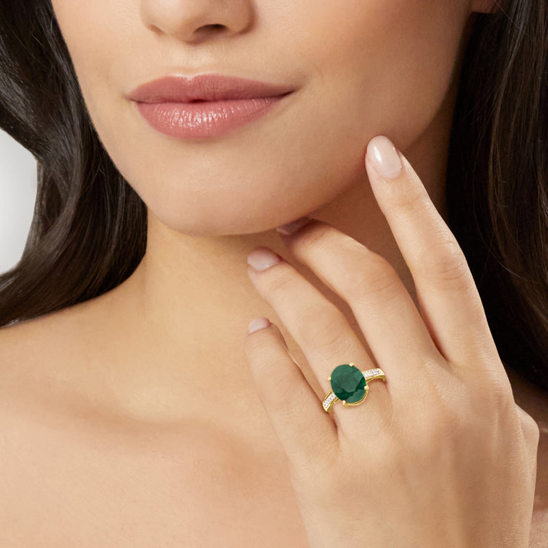 Green emerald ring on hand with diamond accents in 10kt yellow gold