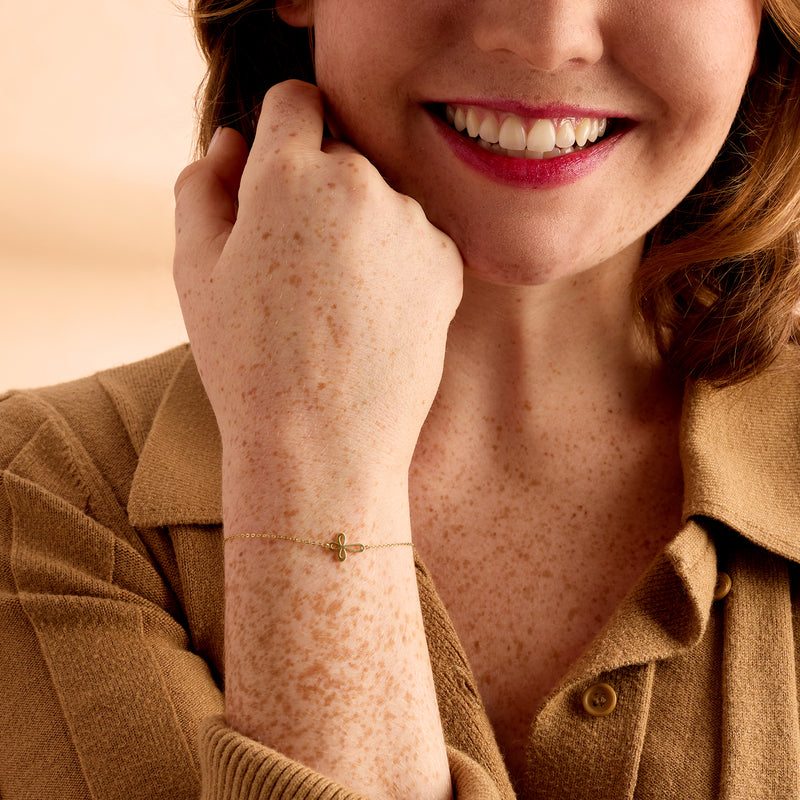 14kt yellow gold cross loop bracelet on wrist, small looped cross charm