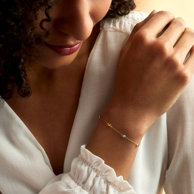 14kt yellow gold multi-gem bracelet worn on wrist, round colorful stones along the chain