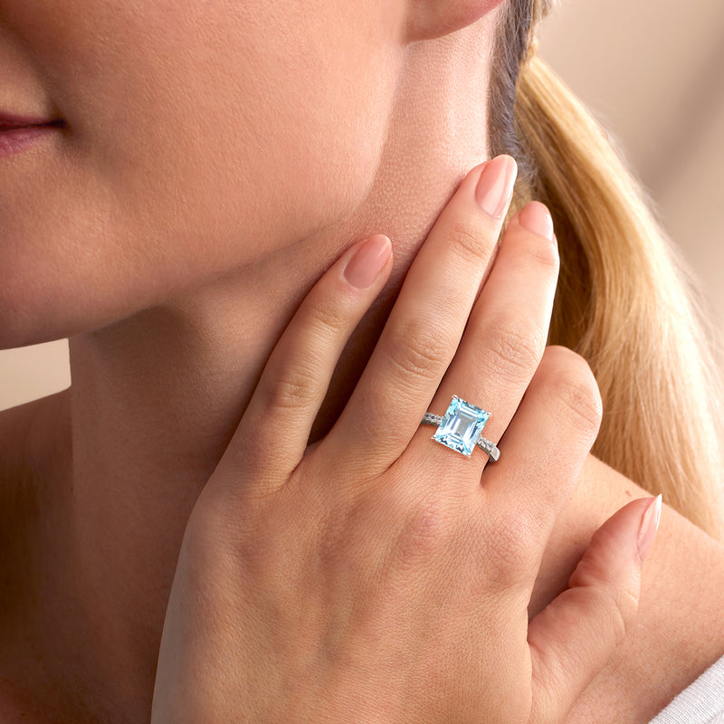 Sky blue topaz ring in sterling silver on finger, rectangular stone with white accents
