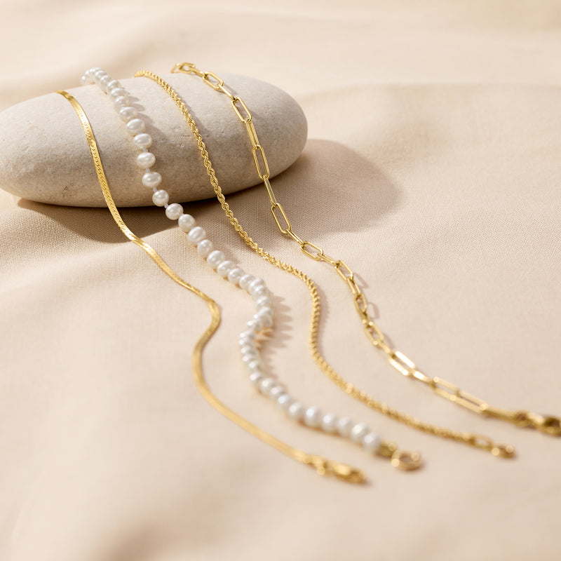 Yellow gold herringbone anklet on jewelry display; chain links and clasp visible