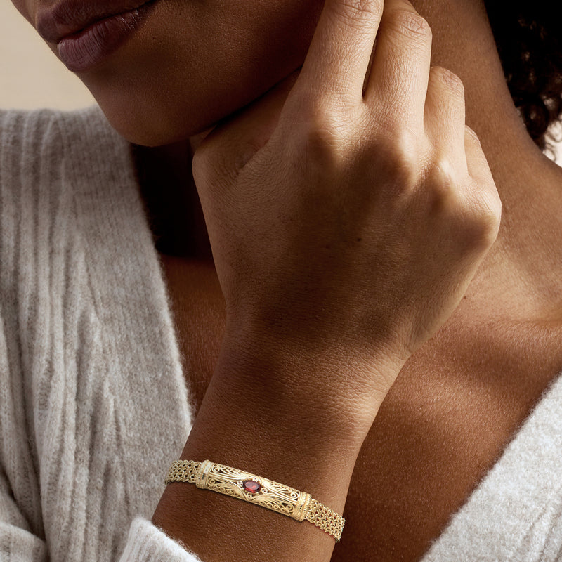 Filigree gold bracelet with red garnet centerpiece on wrist