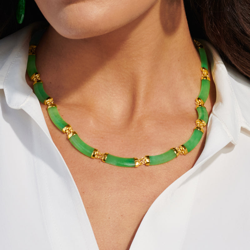 Curved green jade bead necklace with gold-toned spacers worn with a white shirt