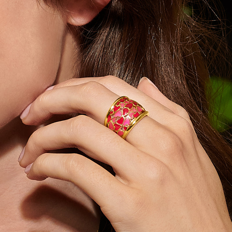 Gold enamel heart ring with red and pink heart mosaic, close-up on hand