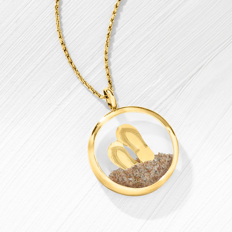 Round 14kt yellow gold sand pendant with sand-filled center, suspended on chain