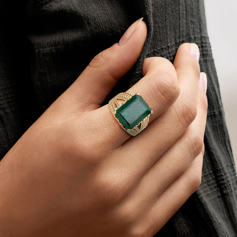 Gold-tone ring with emerald green square-cut gemstone, prong-set on a hand