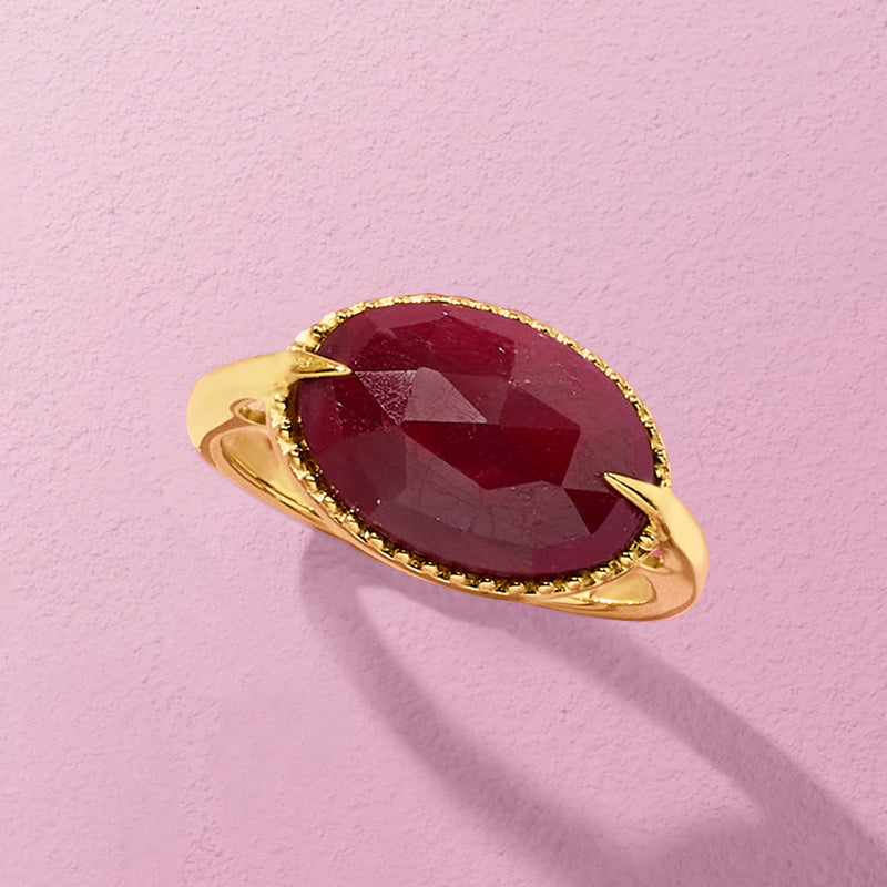 Oval ruby gemstone ring with scalloped gold edge and small-stone halo, angled view