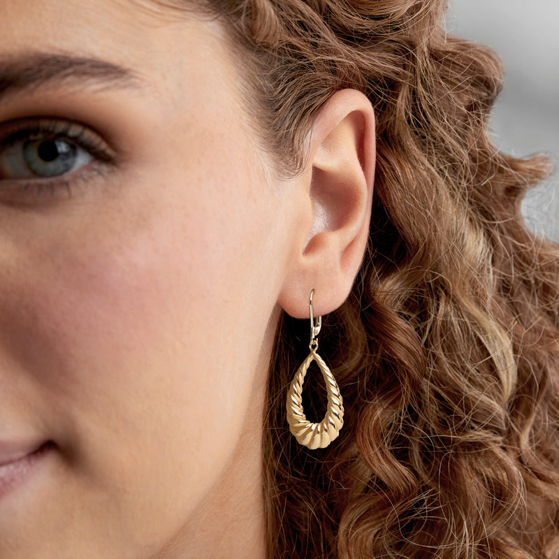 Gold twisted teardrop leverback earrings worn on ear, textured rope tear drops.