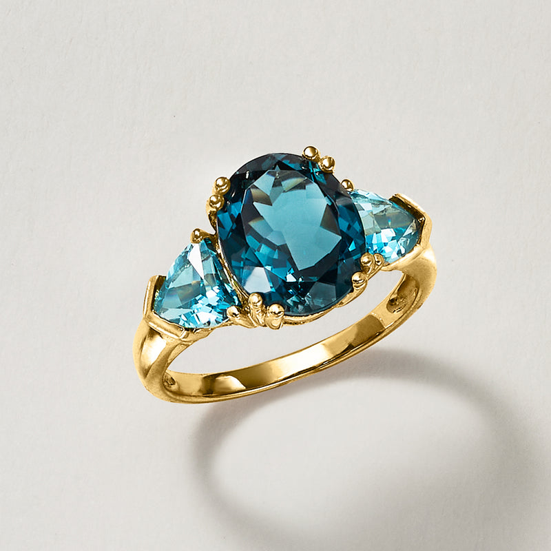 14kt yellow gold three-stone ring with oval blue topaz center and two side light-blue stones