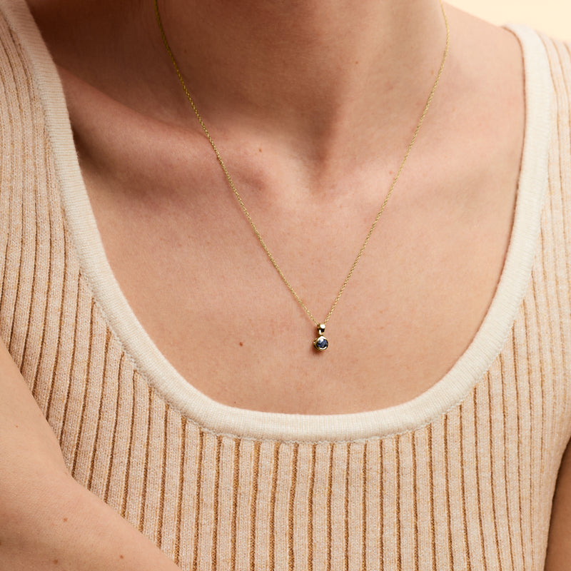 14kt yellow gold sapphire pendant necklace with small round blue stone, close-up