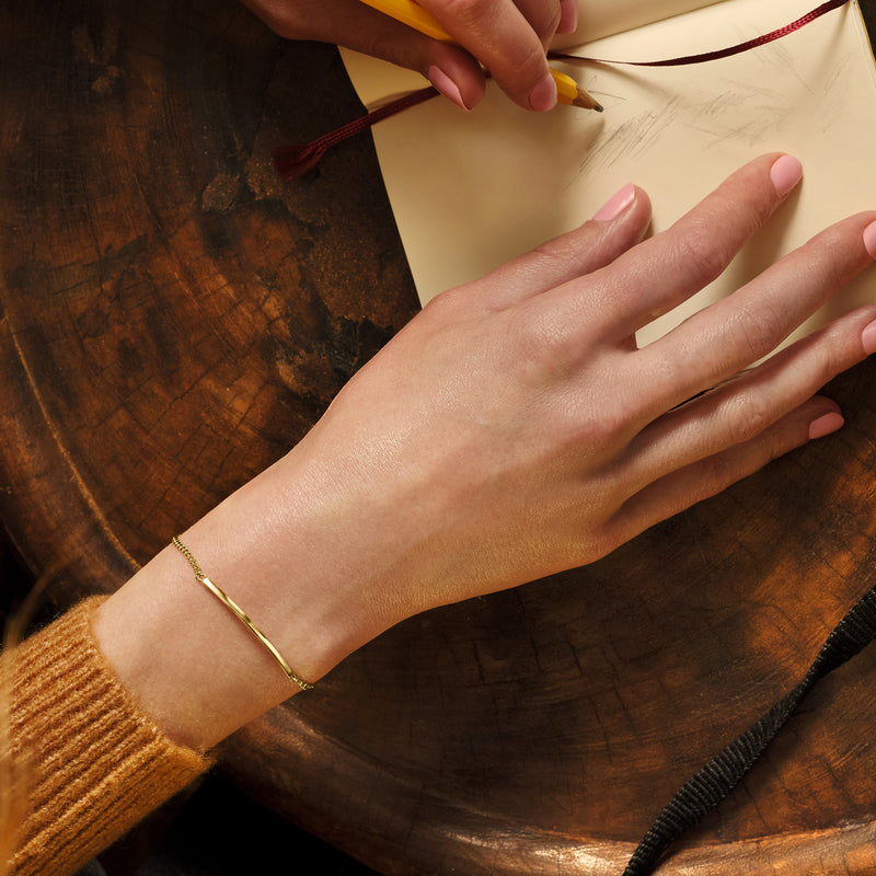 10kt yellow gold curb-link bar bracelet on forearm, round-ring clasp and flat bar