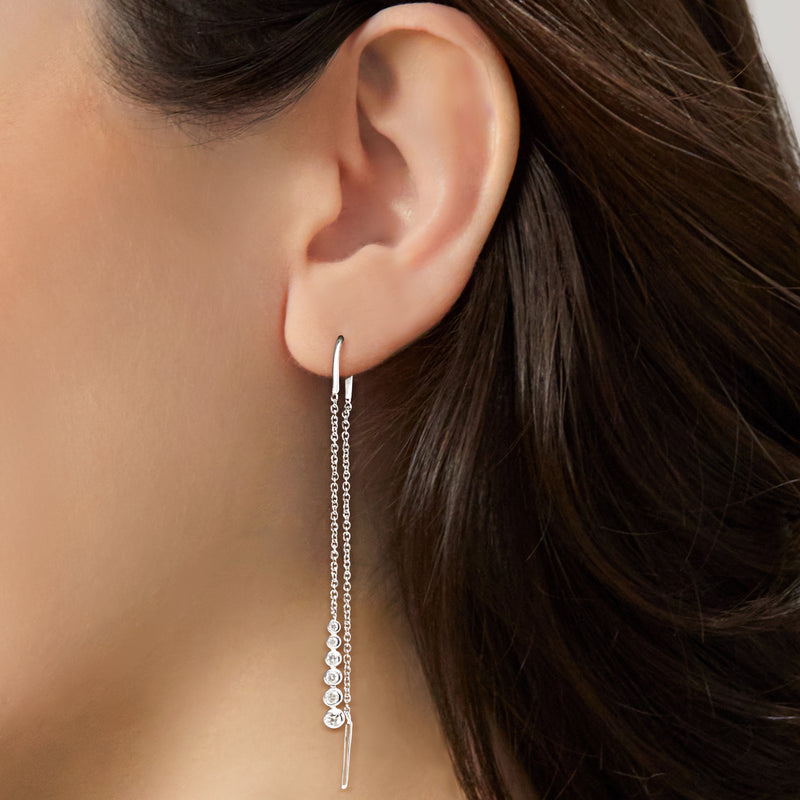 Diamond threader earrings with round bezel-set stones on sterling silver, close-up on ear