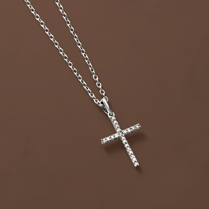 Sterling silver cross pendant necklace with sparkling stones, angled on a chain.