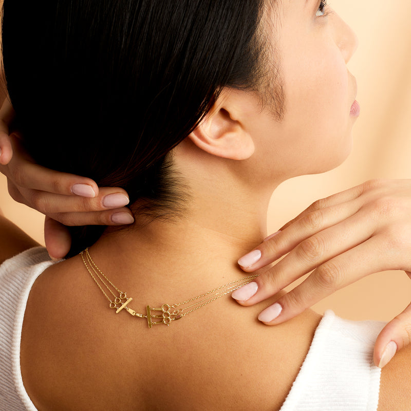 Yellow gold layering clasp detail on layered necklace at collarbone