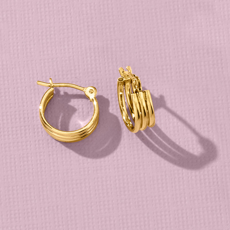 Three-row huggie hoop earrings in polished yellow gold, stacked hoop profile.