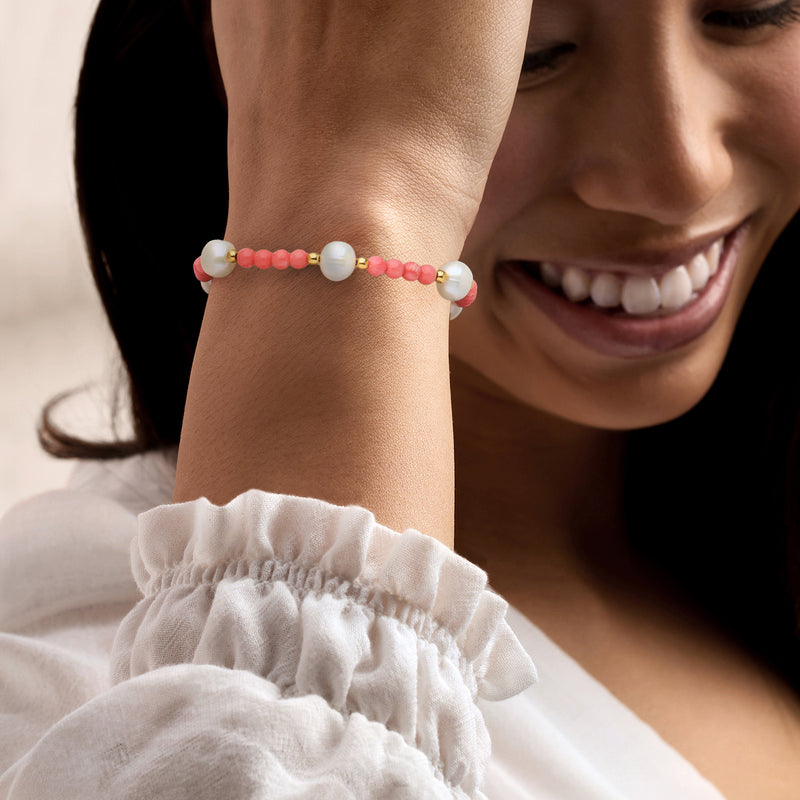 Pink coral bead bracelet with white cultured pearls and gold clasp on wrist