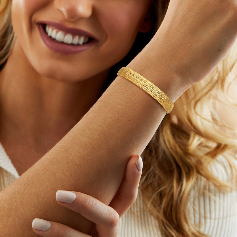 Gold textured bracelet on wrist with polished hinged clasp visible